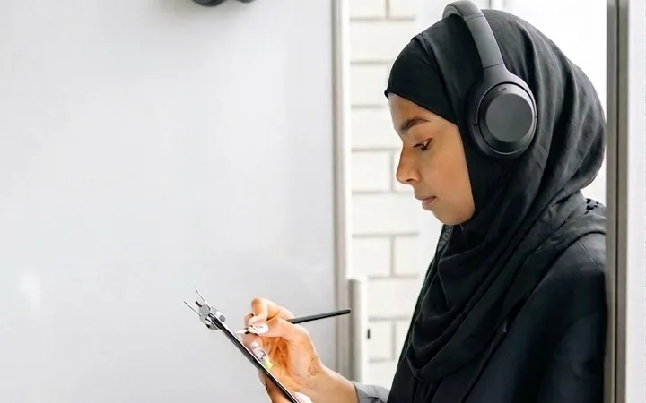 A call centre agent wearing a headset and taking notes on a clipboard